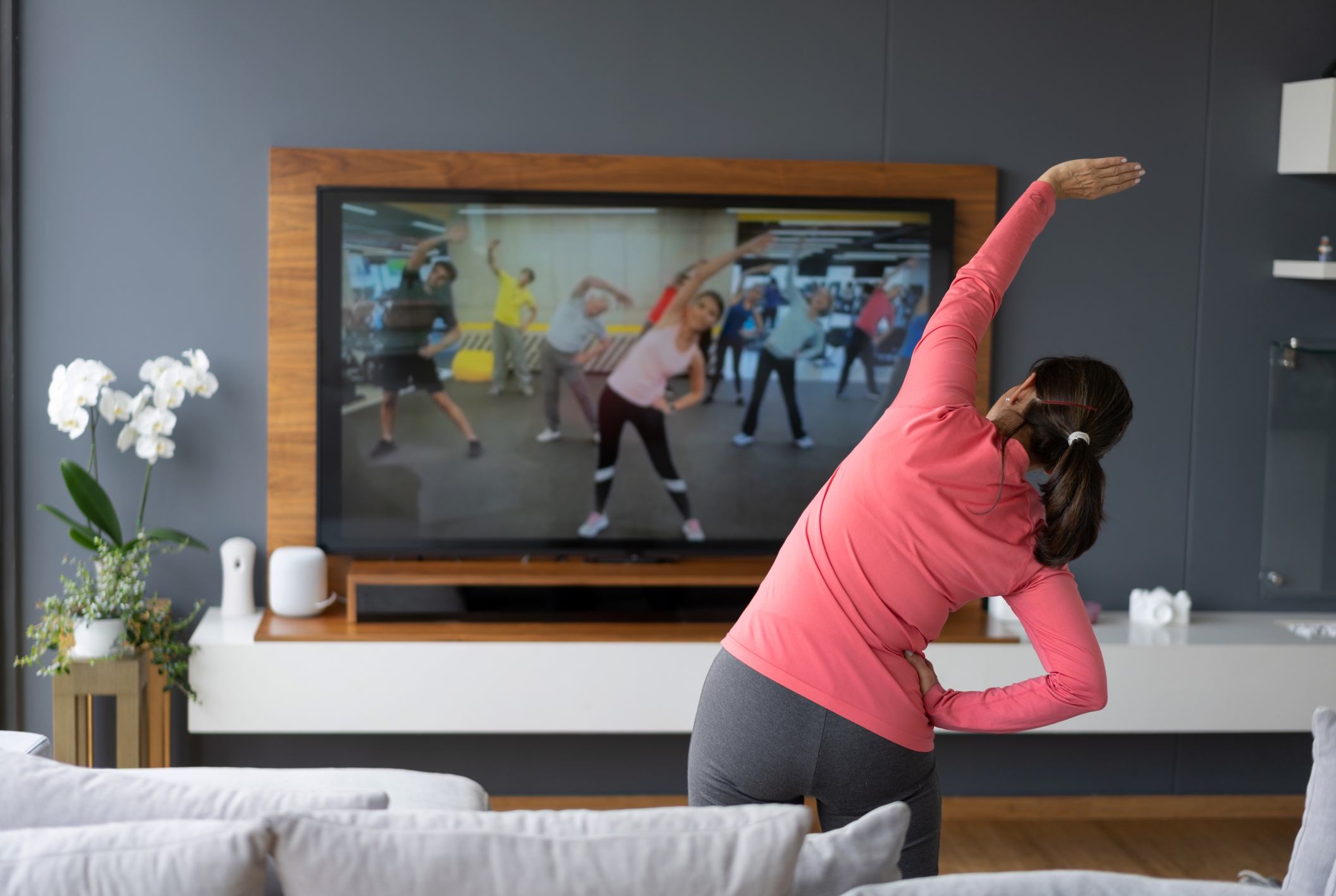 Woman watching indoor exercise tips on tv for exercise in winter