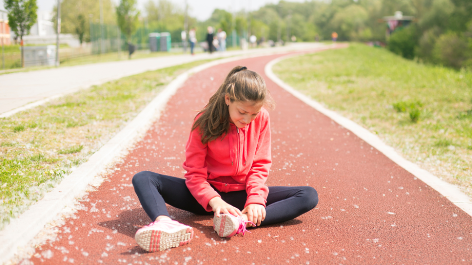 Girl clutching her sprained ankle while exercising