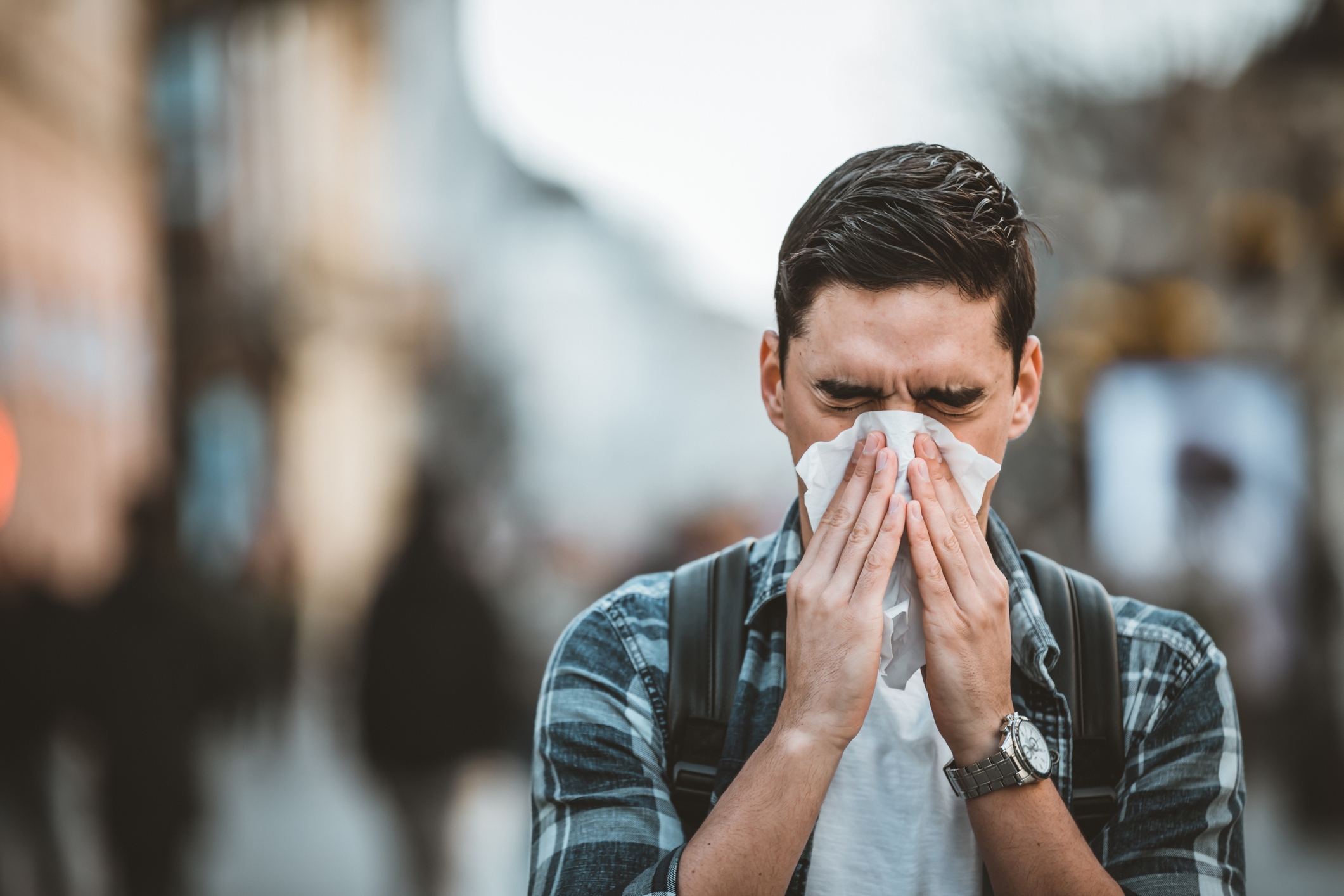 Man experiencing spring allergies blowing nose