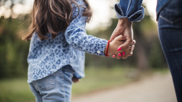 Young girl with childhood eczema holding her mother’s hand