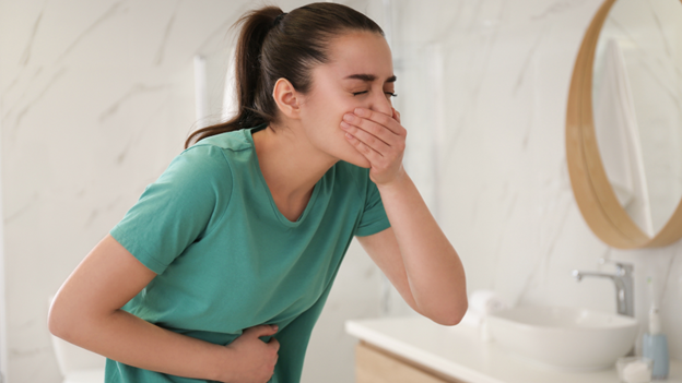 Woman holding stomach experiencing vomiting from stomach flu