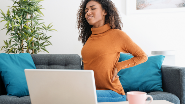 Woman in orange sweater experiencing pain from a pulled muscle in back