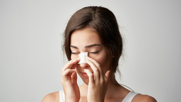 A woman with a broken nose touching her bandaged nose