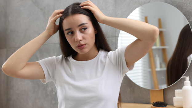 A woman with an itchy scalp due to dandruff