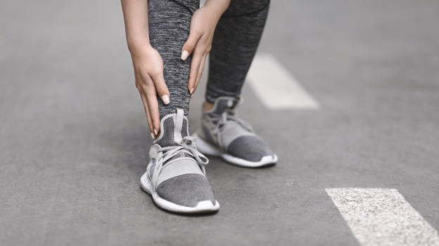 A woman grabbing her shin in need of shin splint treatment