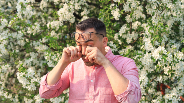 A man rubbing his eyes due to severe symptoms of environmental allergies