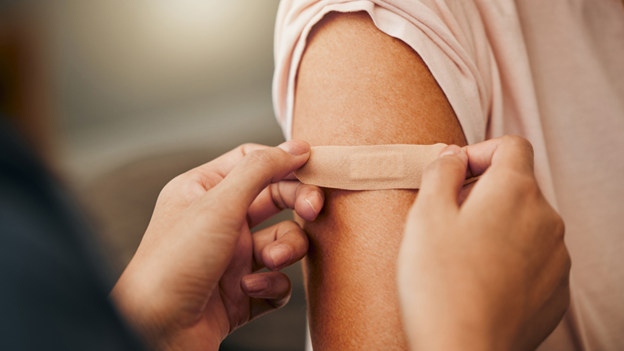 A doctor placing a bandaid on a patient's arm after treating an infected cut