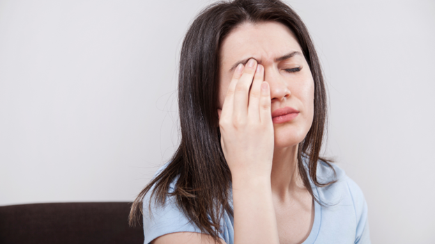 A woman with a scratched cornea holding her eye