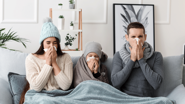 Family with contagious flu blowing their noses from common flu symptoms