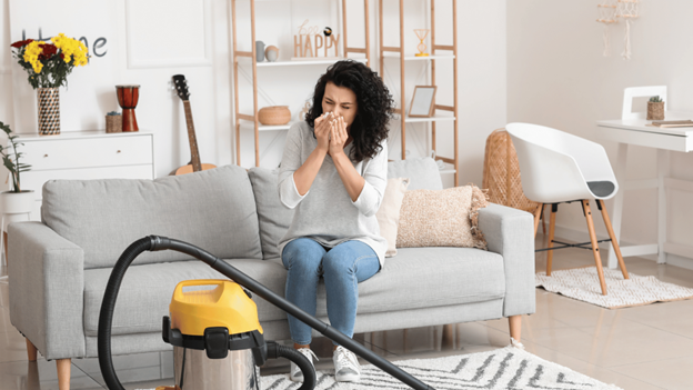 A woman dealing with allergic asthma attacks from vacuuming dust