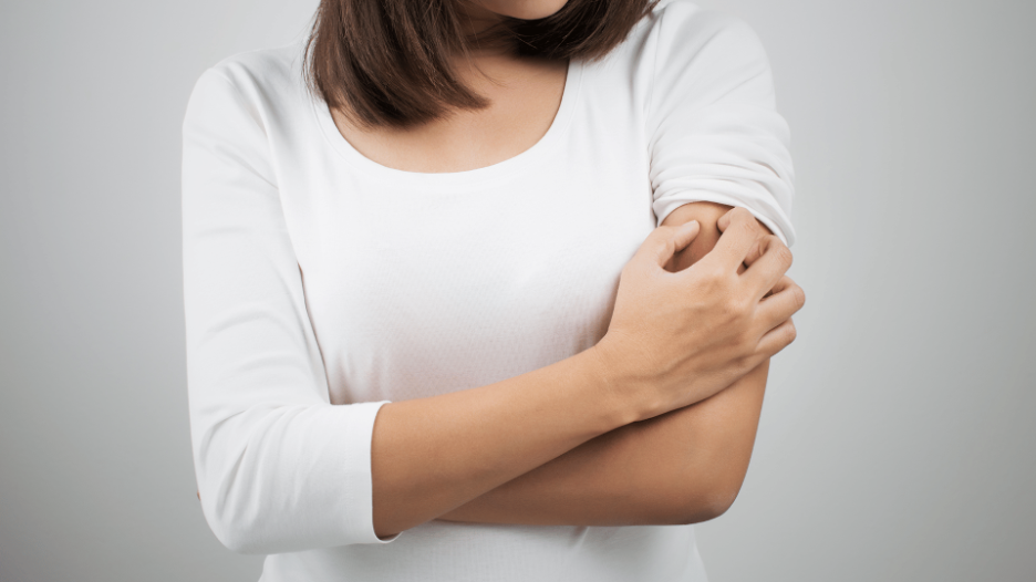 Person scratching their arm, indicating itchy skin, a common issue treated at CityMD urgent care