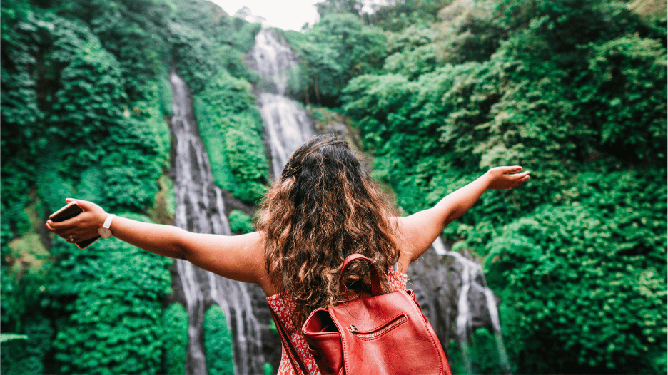 Traveler enjoying a scenic waterfall view during safe summer travel