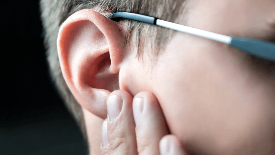 Close-up of a person experiencing ear congestion, touching their ear in discomfort, seeking relief for clogged ears