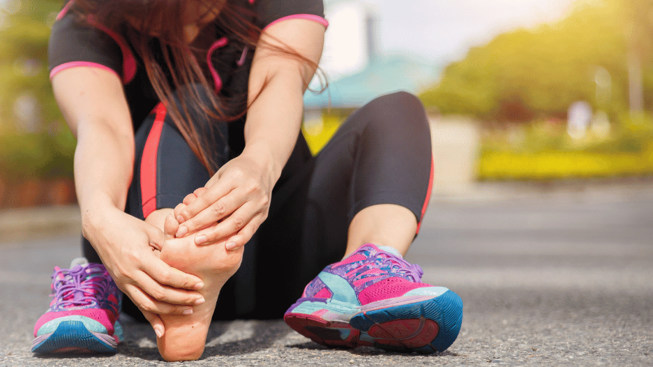 Active woman grasping her toe, suffering from a case of turf toe