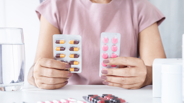 Woman holding up various pills, representing antibiotics for sinus infections