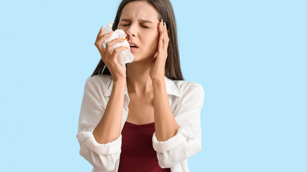 Woman holding a tissue to stop a nosebleed, highlighting concerns about when to worry about nosebleeds and seek medical care