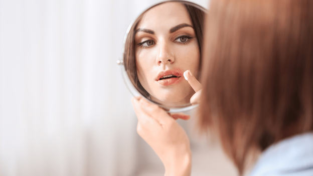 Woman looking at a canker sore in the mirror