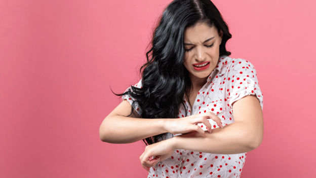 Adult woman with irritated skin scratching her arm, showing a possible symptom of chickenpox in adults