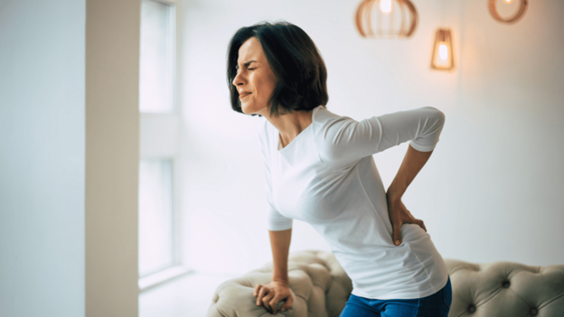 Woman with lower left back pain grasping her lower back